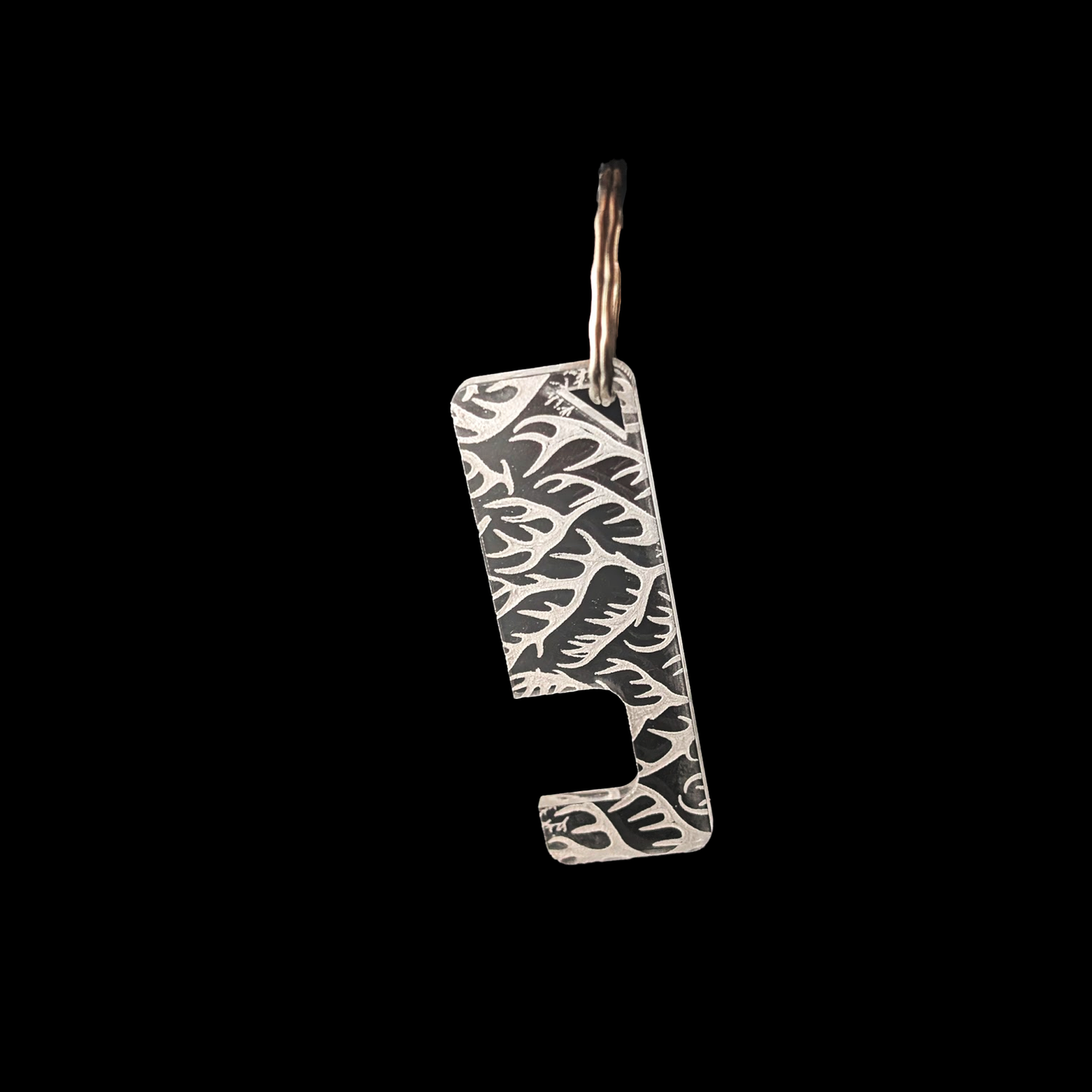 a transparent phone stand key ring with an engraved antler texture against a black background. Rua phone stand by Fiach Rua