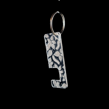 a transparent phone stand key ring with an engraved caterpillar texture against a black background. Rua phone stand by Fiach Rua