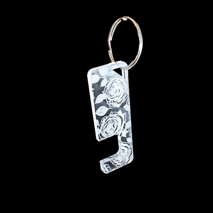 a transparent phone stand key ring with an engraved Rose texture against a black background. Rua phone stand by Fiach Rua